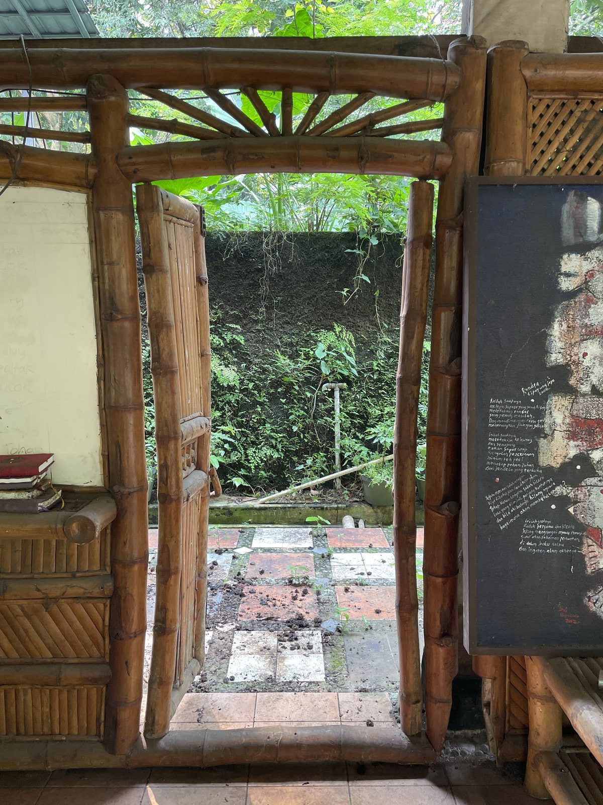Bamboo doorframe, Bengkel Teater Rendra compound — poem on blackboard to the right